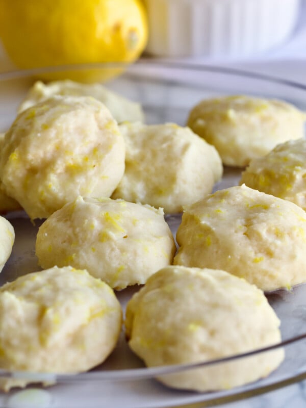 lemon ricotta cookies on a clear plate with a lemon