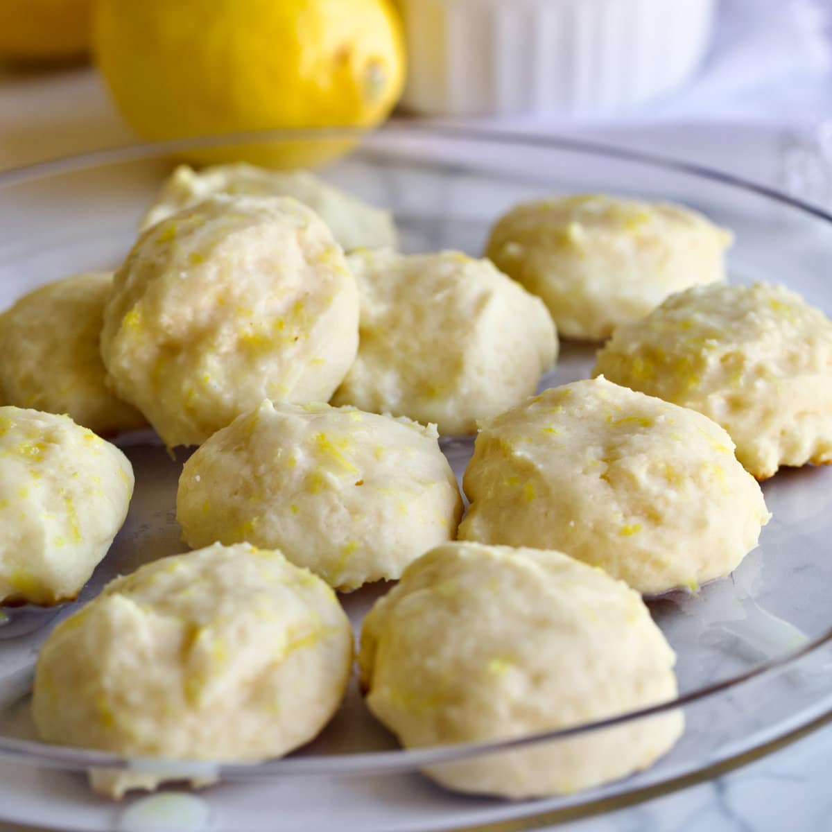 lemon ricotta cookies on a clear plate with a lemon