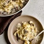 plated black truffle cream sauce pasta with truffle cream sauce on the side.