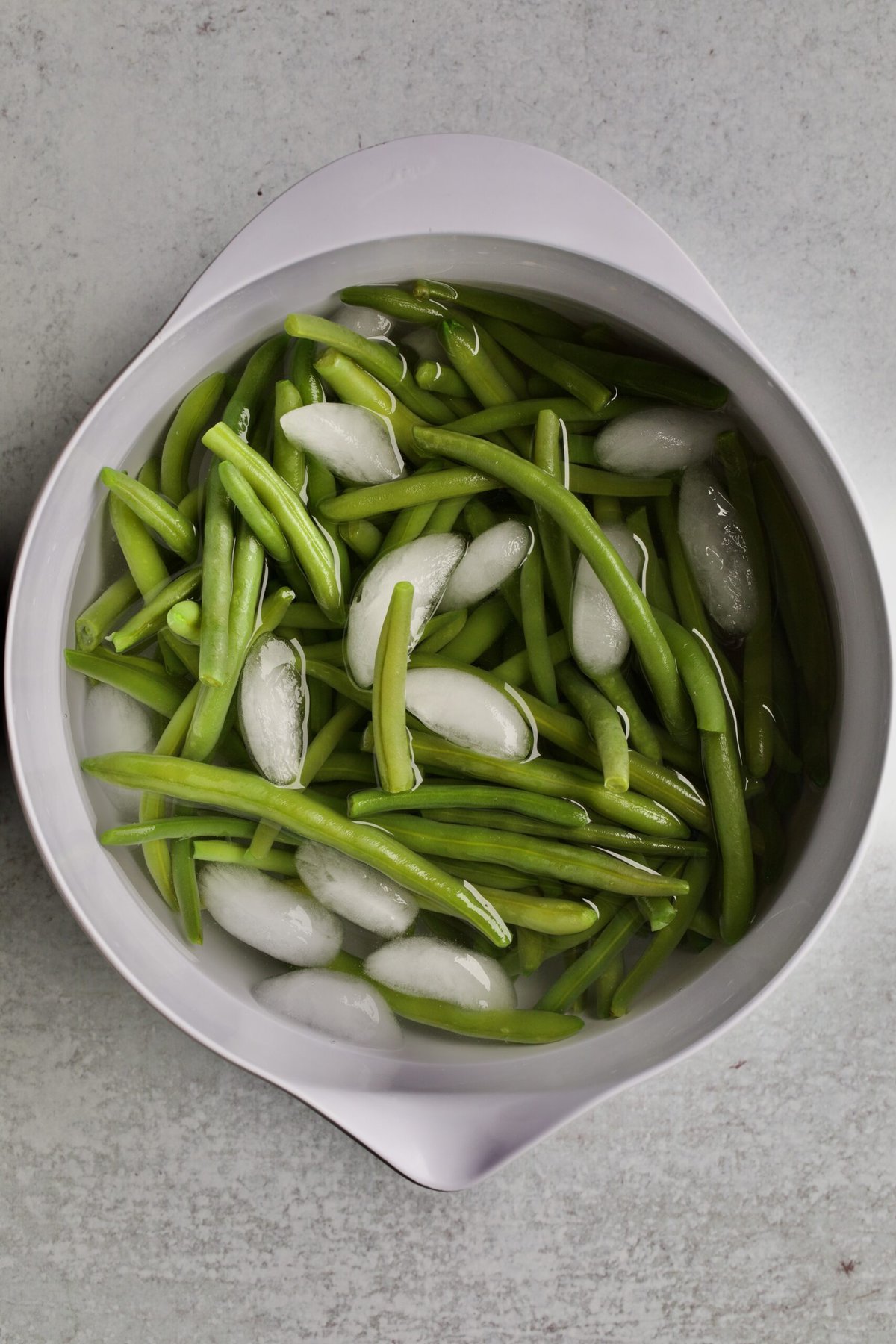 process of making sautéed green beans: placing the green beans in ice water.