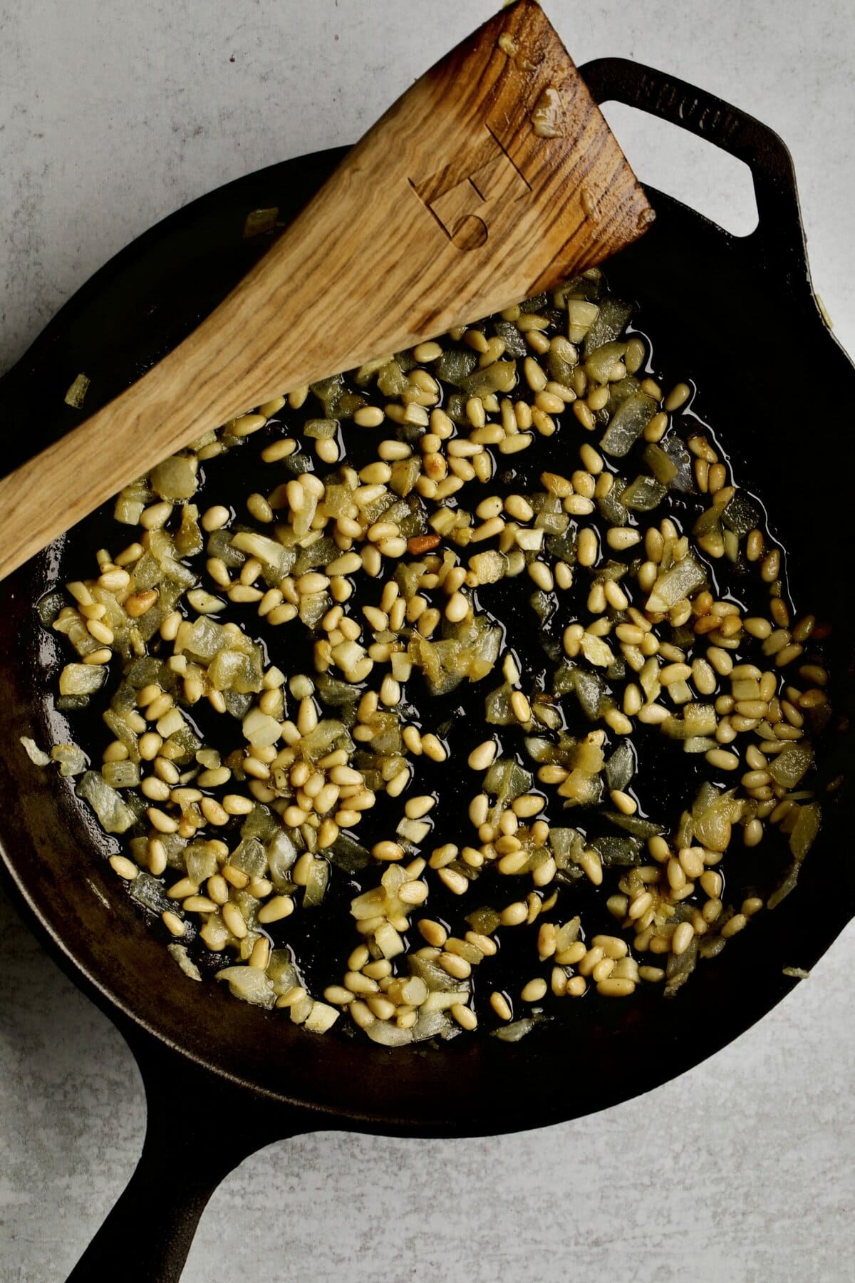 process of making sautéed green beans: frying the onions and pine nuts.