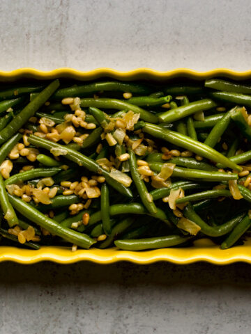 Sautéed Frozen Green Beans Recipe (Easy) on a yellow serving platter.