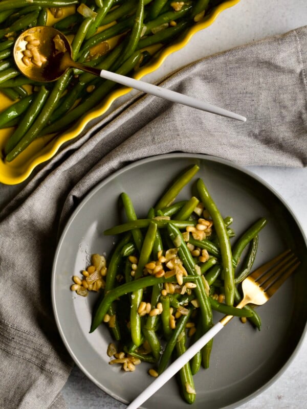 Sautรฉed Frozen Green Beans Recipe (Easy) on a grey plate with a fork napkin in background.