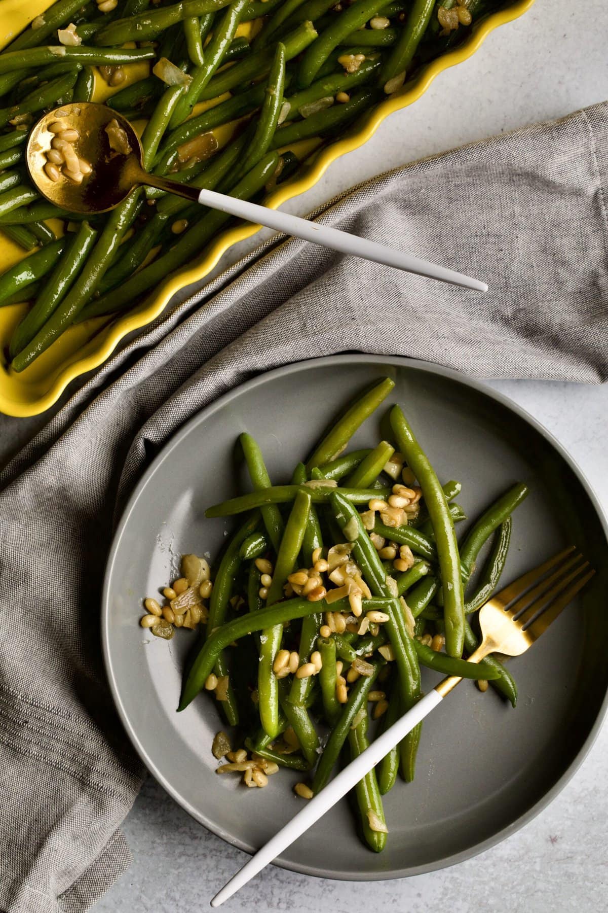 Sautéed Frozen Green Beans Recipe (Easy) on a grey plate with a fork napkin in background.