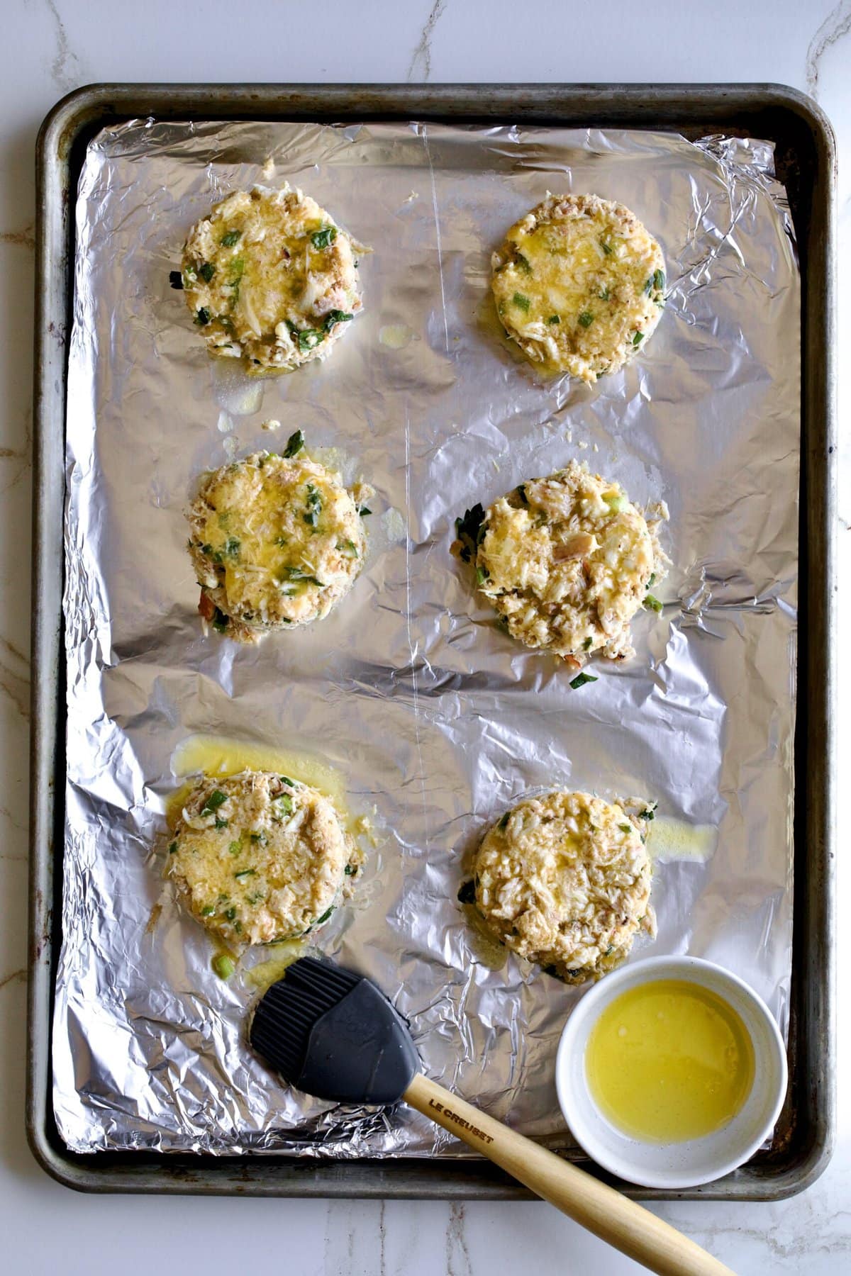 process. butter on top of crab cakes before baking.