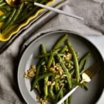 Sautéed Frozen Green Beans Recipe (Easy) on a grey plate with a fork napkin in background.