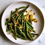 Roasted green beans with garlic and lemon on a plate.