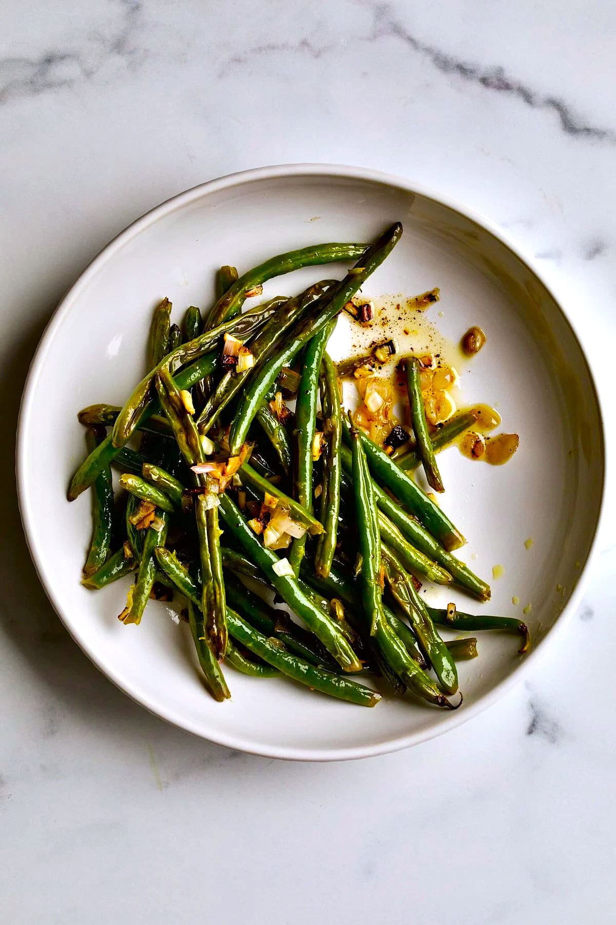 Roasted green beans with garlic and lemon on a plate.