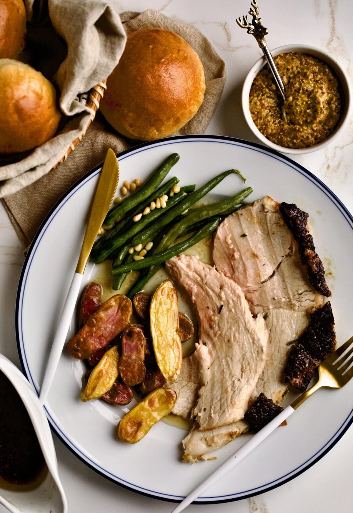 fresh ham roast on a plate with roasted potatoes and green beans. 