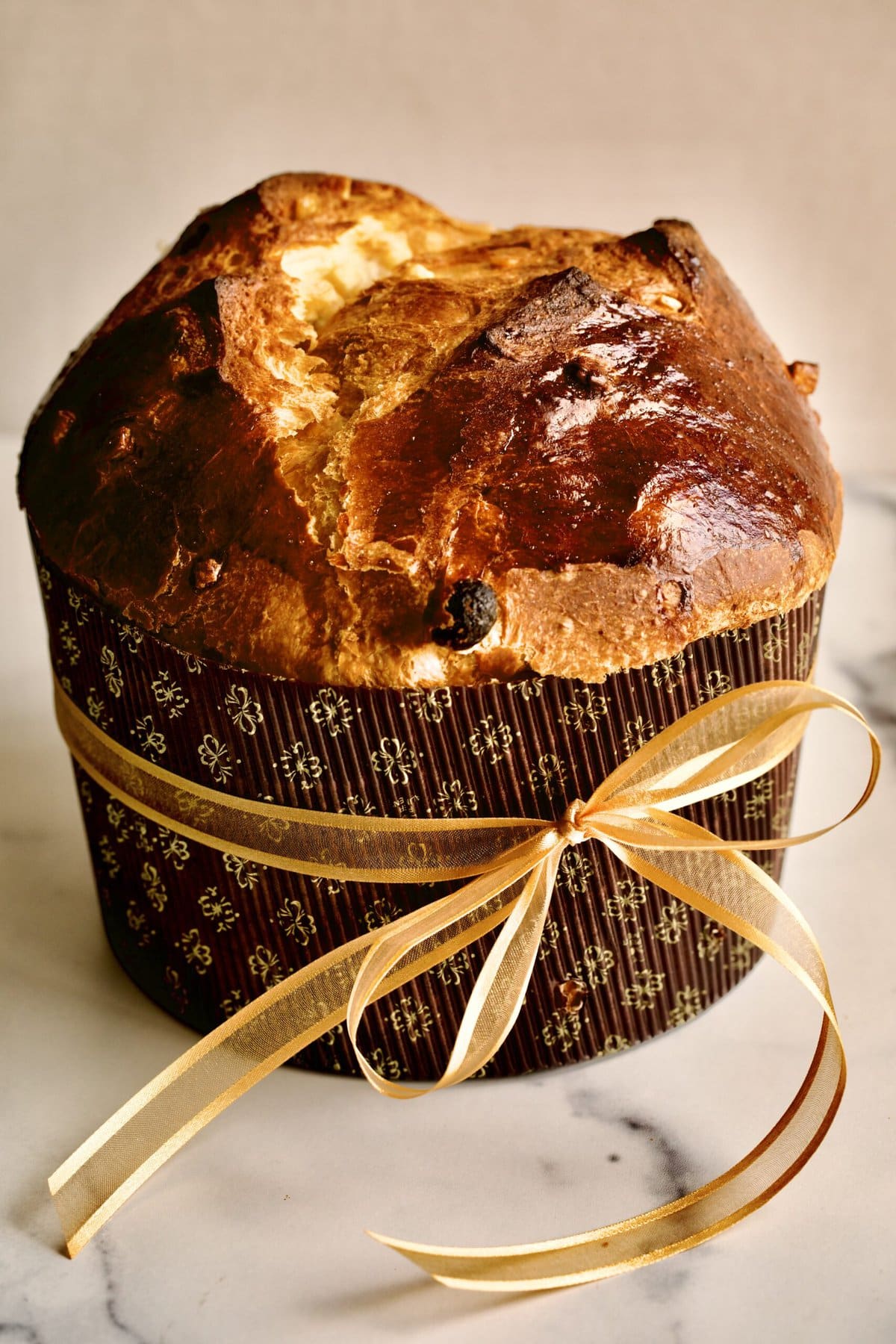 traditional panettone recipe in a paper mold with a ribbon tied around it. 