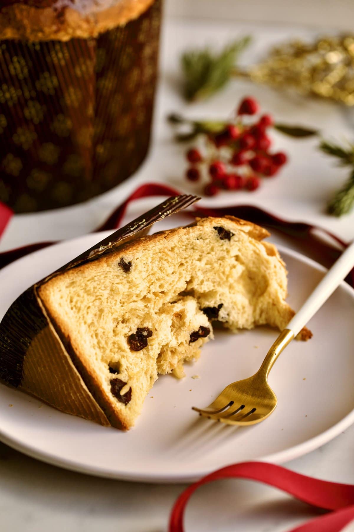 slice of panettone on a plate with Christmas decorations in the background