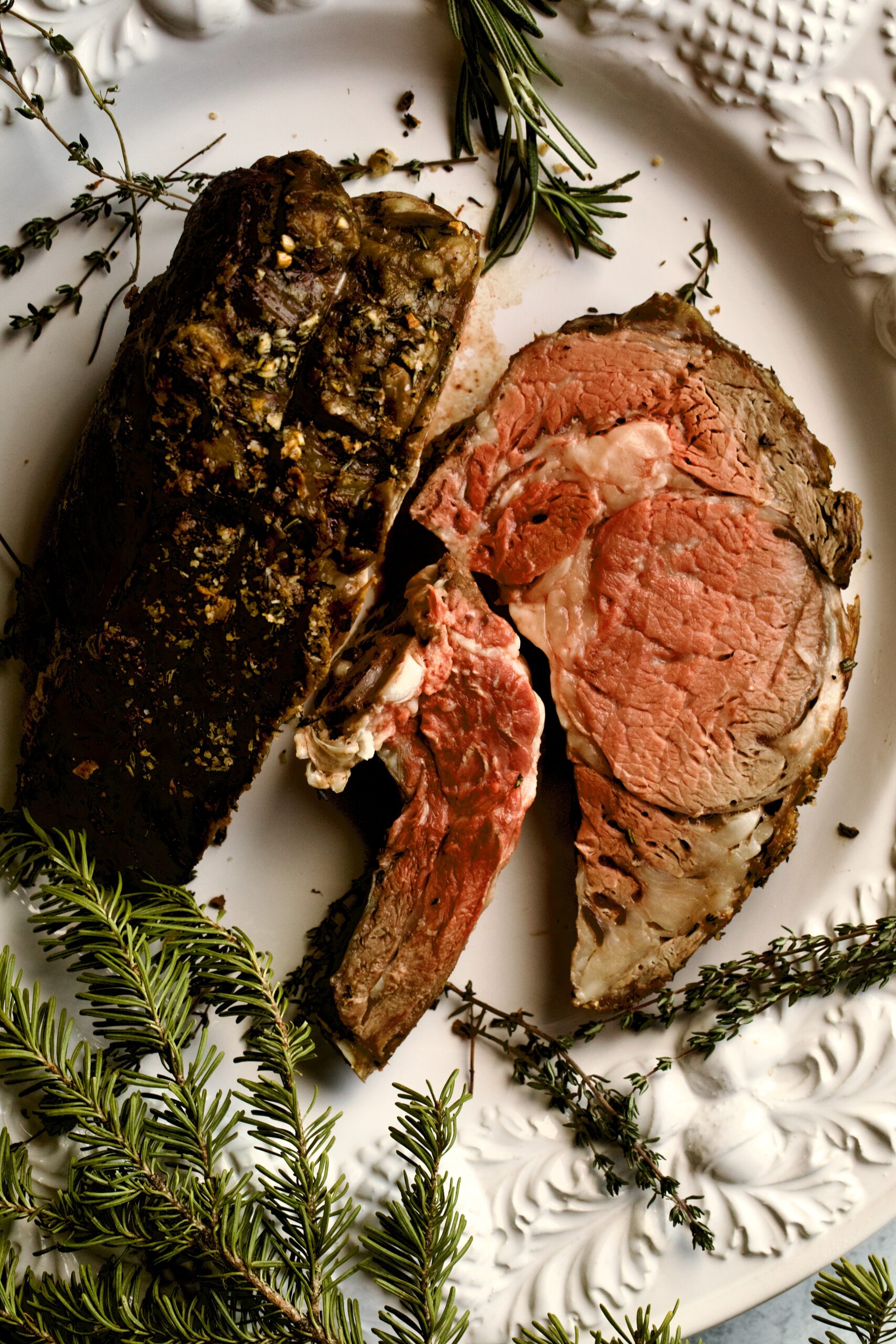 prime rib cut on a large white serving plate.