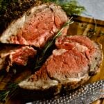 thick slice cut from prim rib roast on a cutting board.