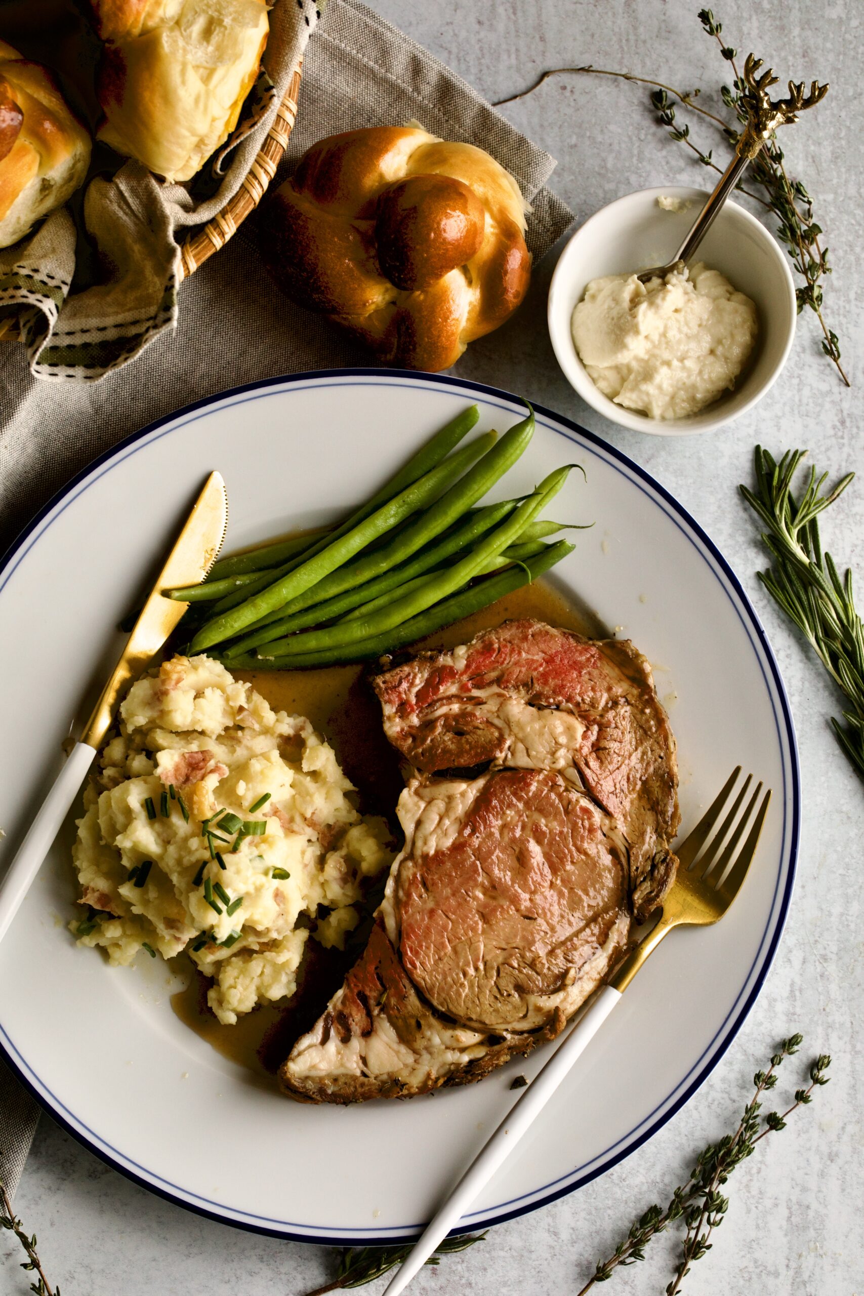 prime rib slice on a plate with garlic red shin mashed potatoes and green beans. 