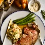 prime rib slice on a plate with garlic red shin mashed potatoes and green beans.