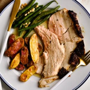 Fresh ham on a plate with potatoes and green beans.