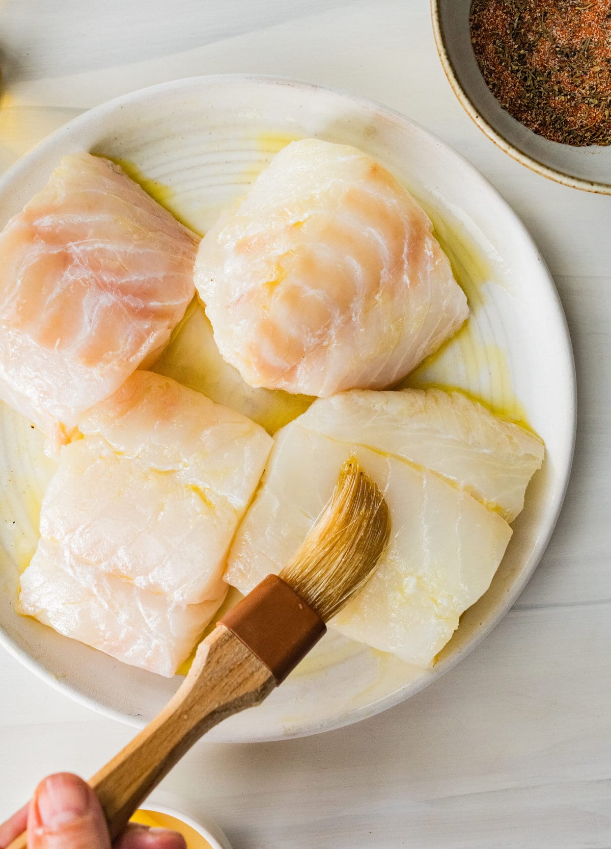 Process for making blackened cod fish- putting oil on fish.