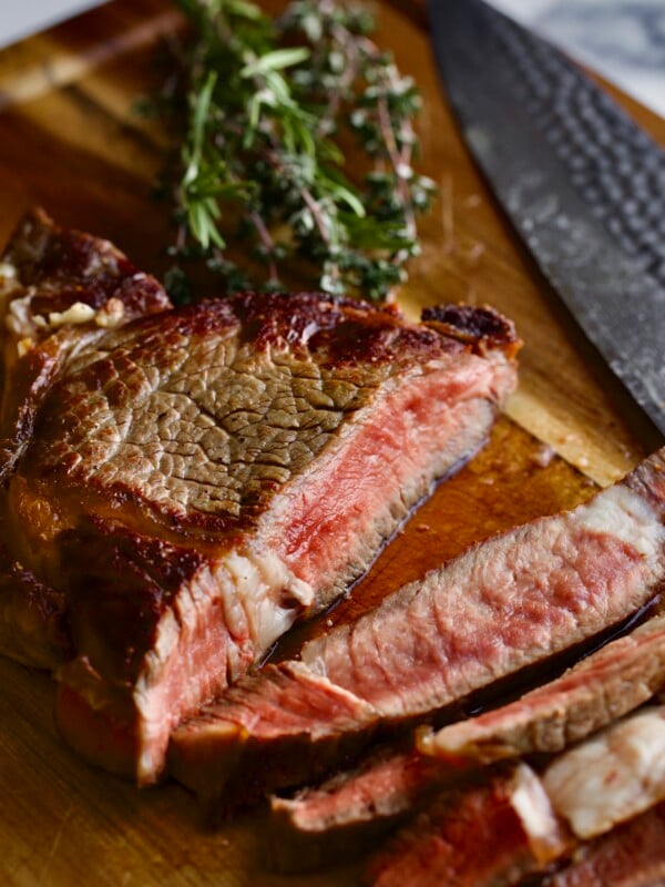 How to Cook Steak in a Pan (Perfect Recipe)- cutting the steak on a cutting board.