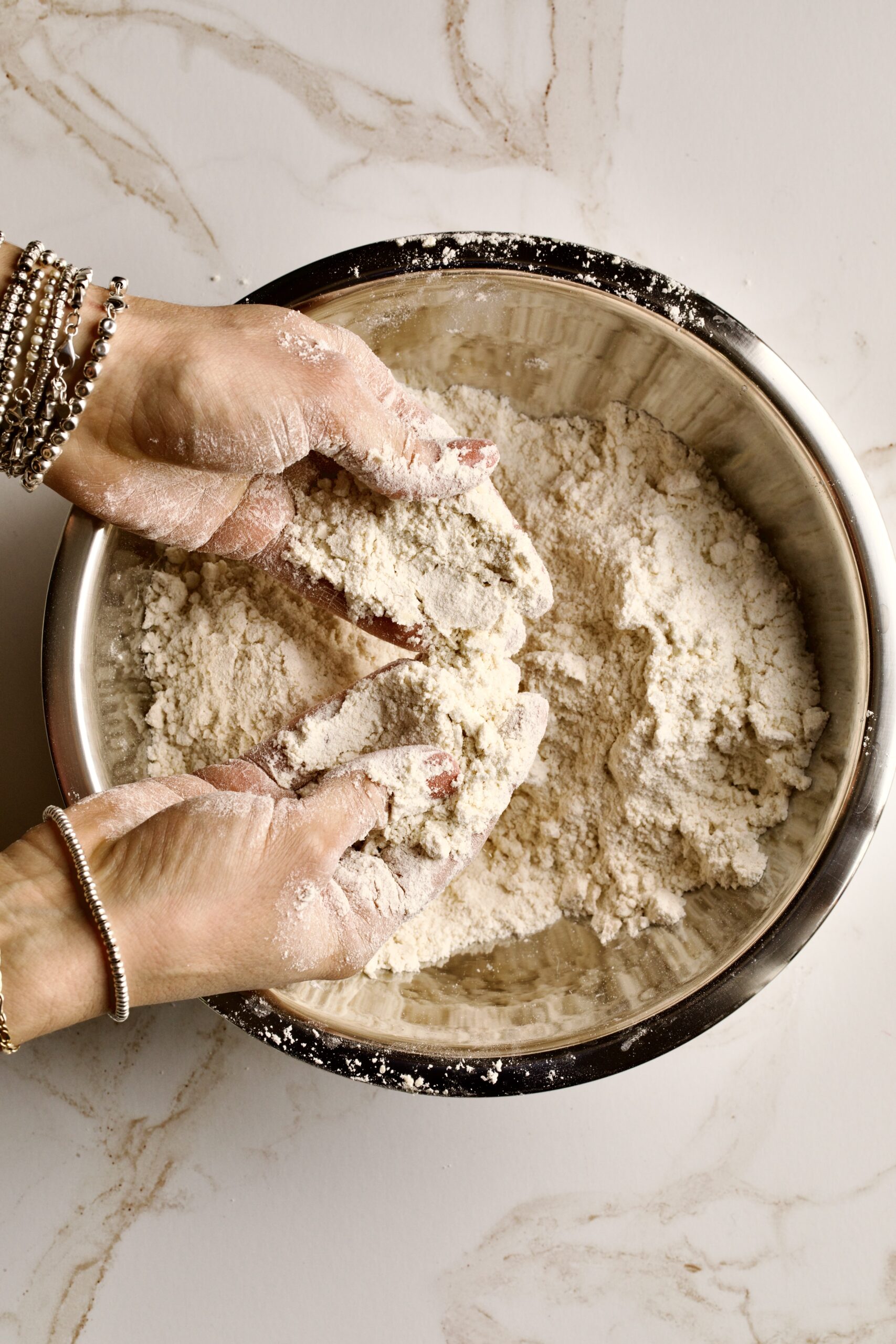 process of making chiacchiere: dry ingredients in a bowl adding in butter. 