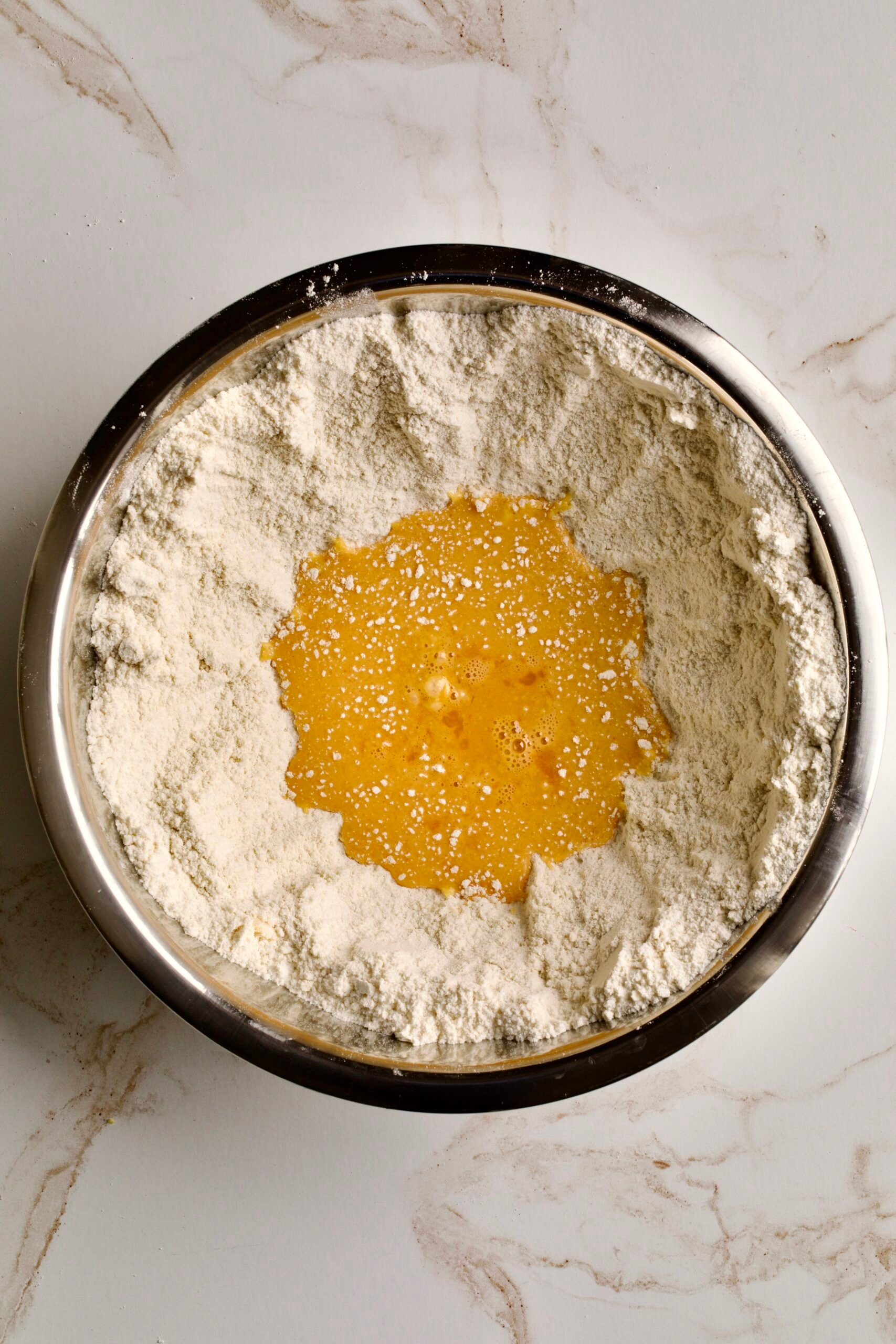 process of making chiacchiere: adding wet ingredients to dry ingredients.