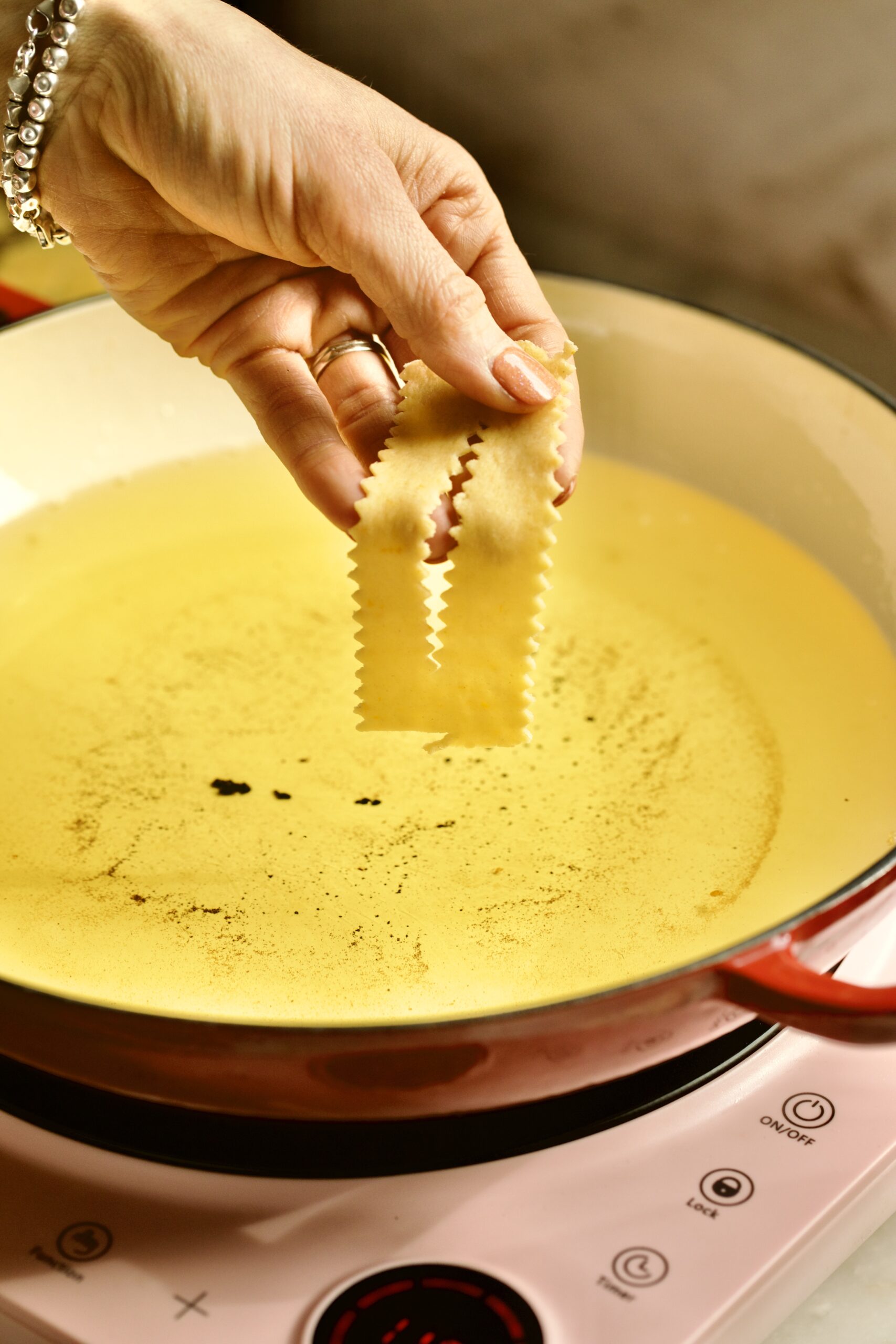 process of making chiacchiere: frying the dough part 1 placing in the hot oil.