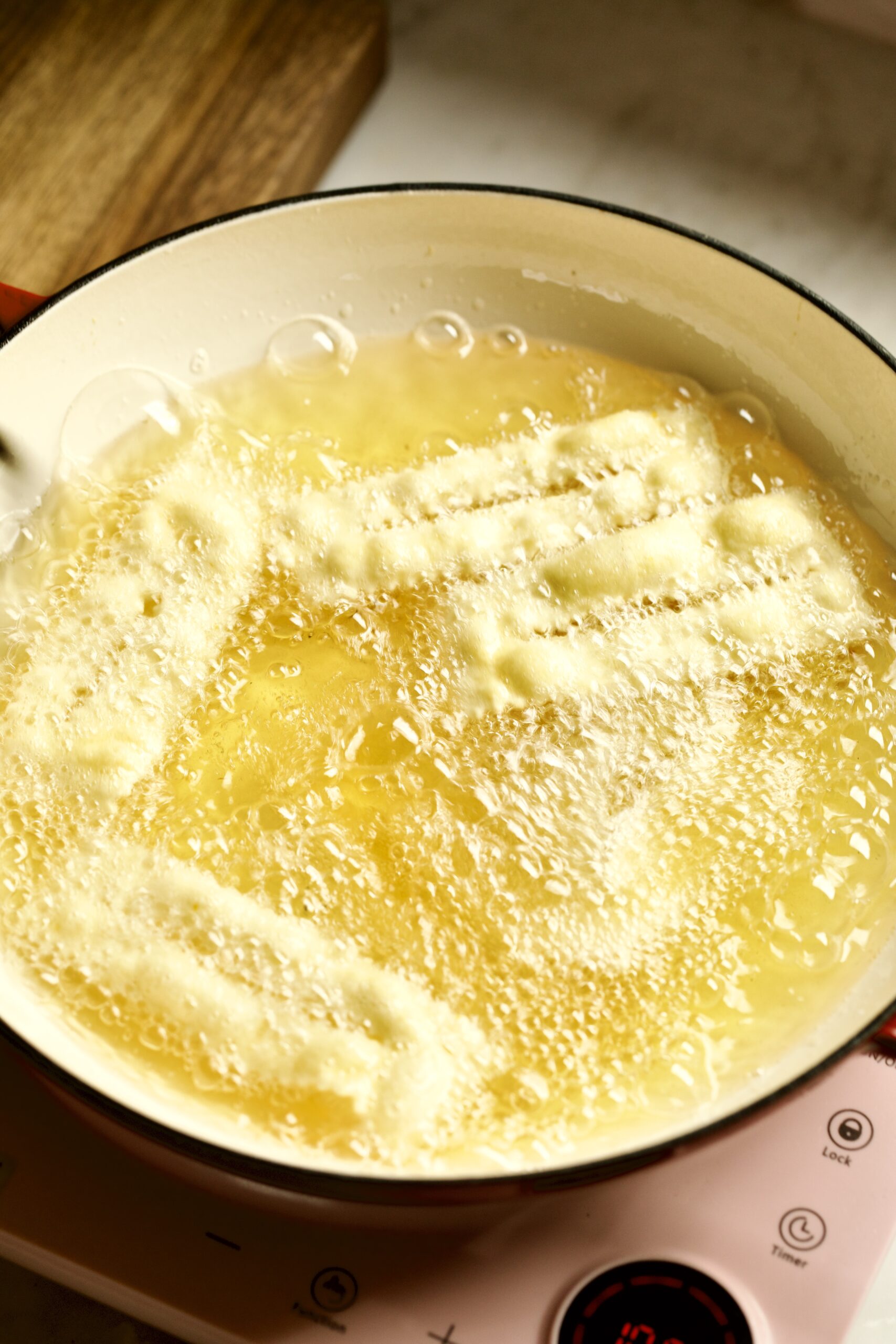 process of making chiacchiere: frying the dough frying in the hot oil taking out with slotted spoon.