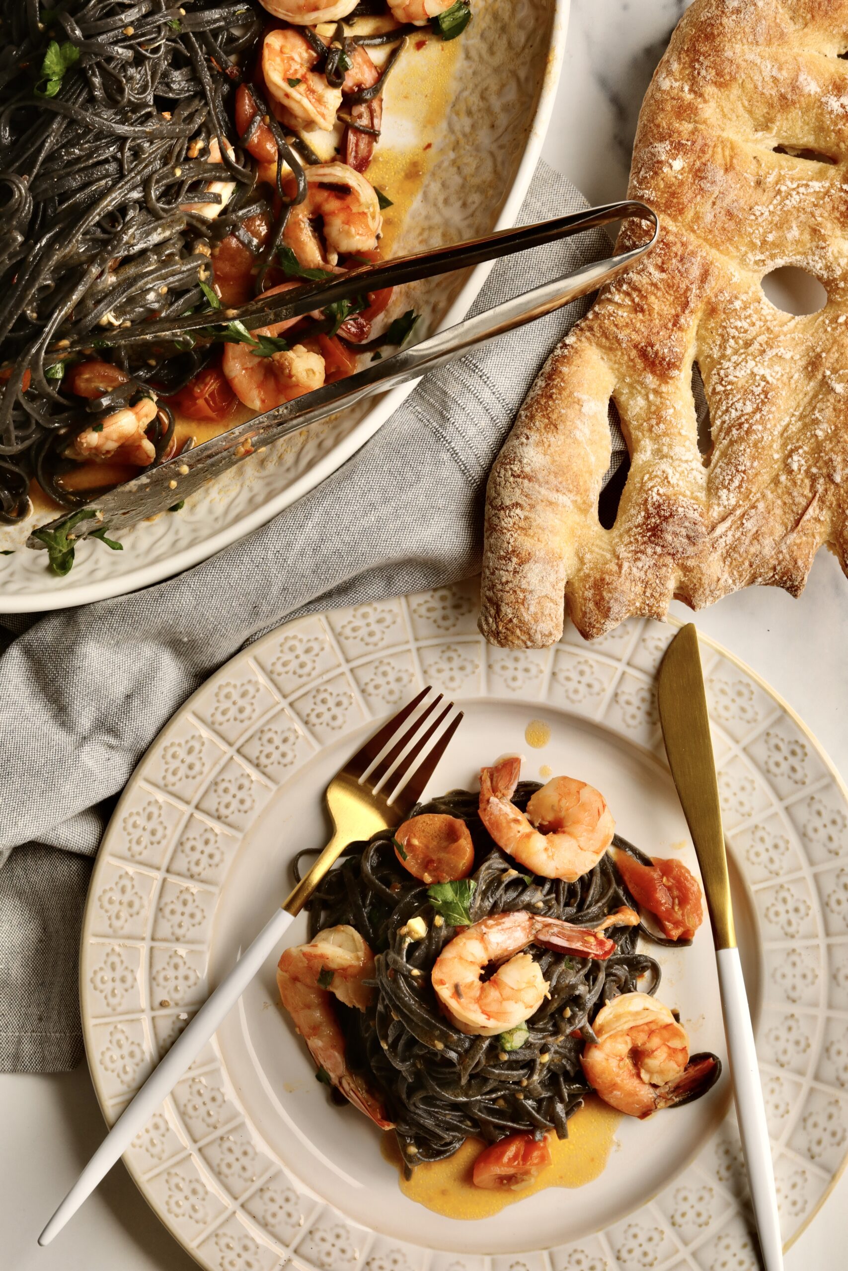 squid ink pasta with shrimp on a plate ready to eat with homemade bread.