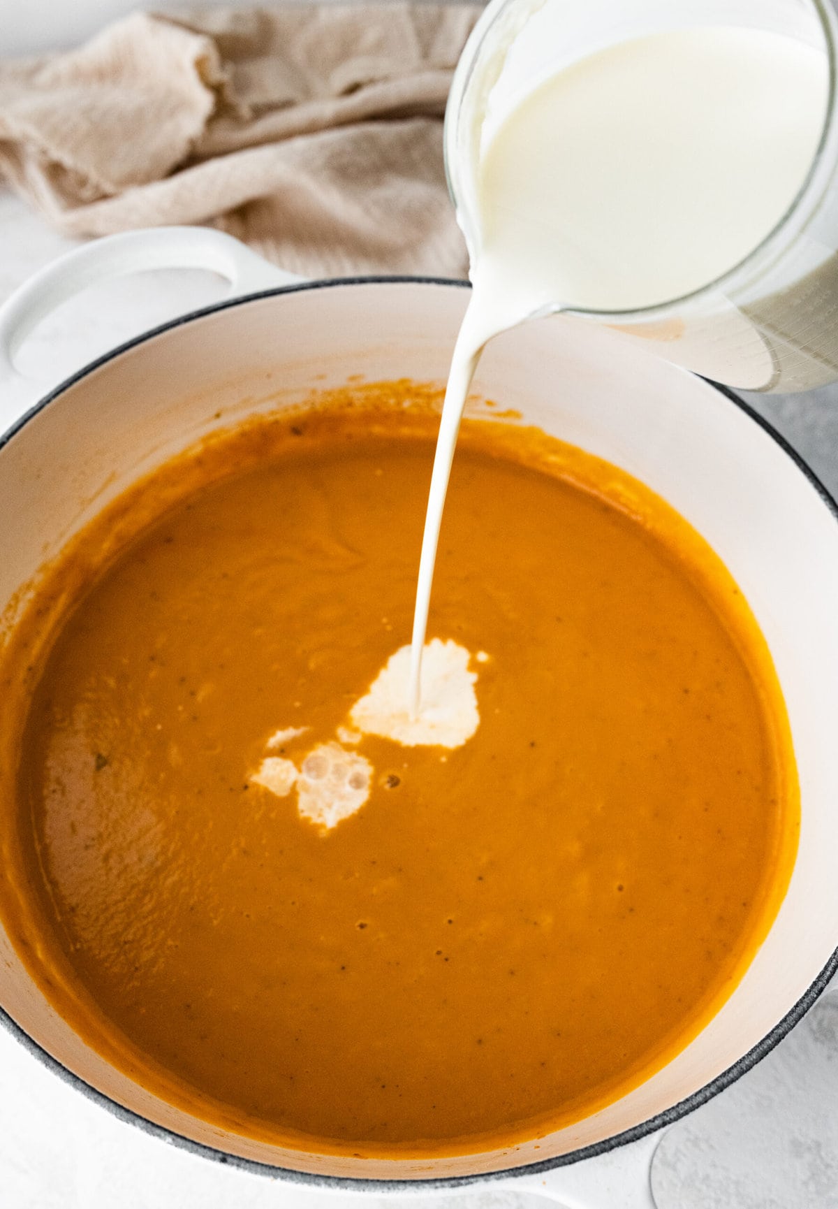 process of making classic lobster bisque: adding cream to pot.