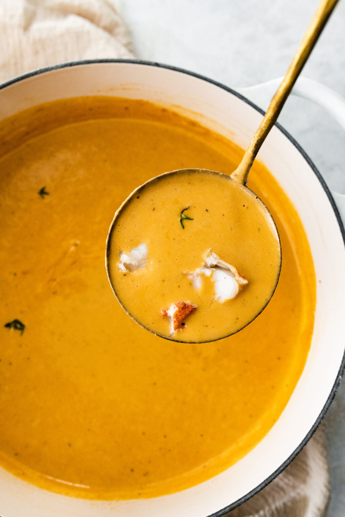 classic lobster bisque in a soup pot with a ladle.