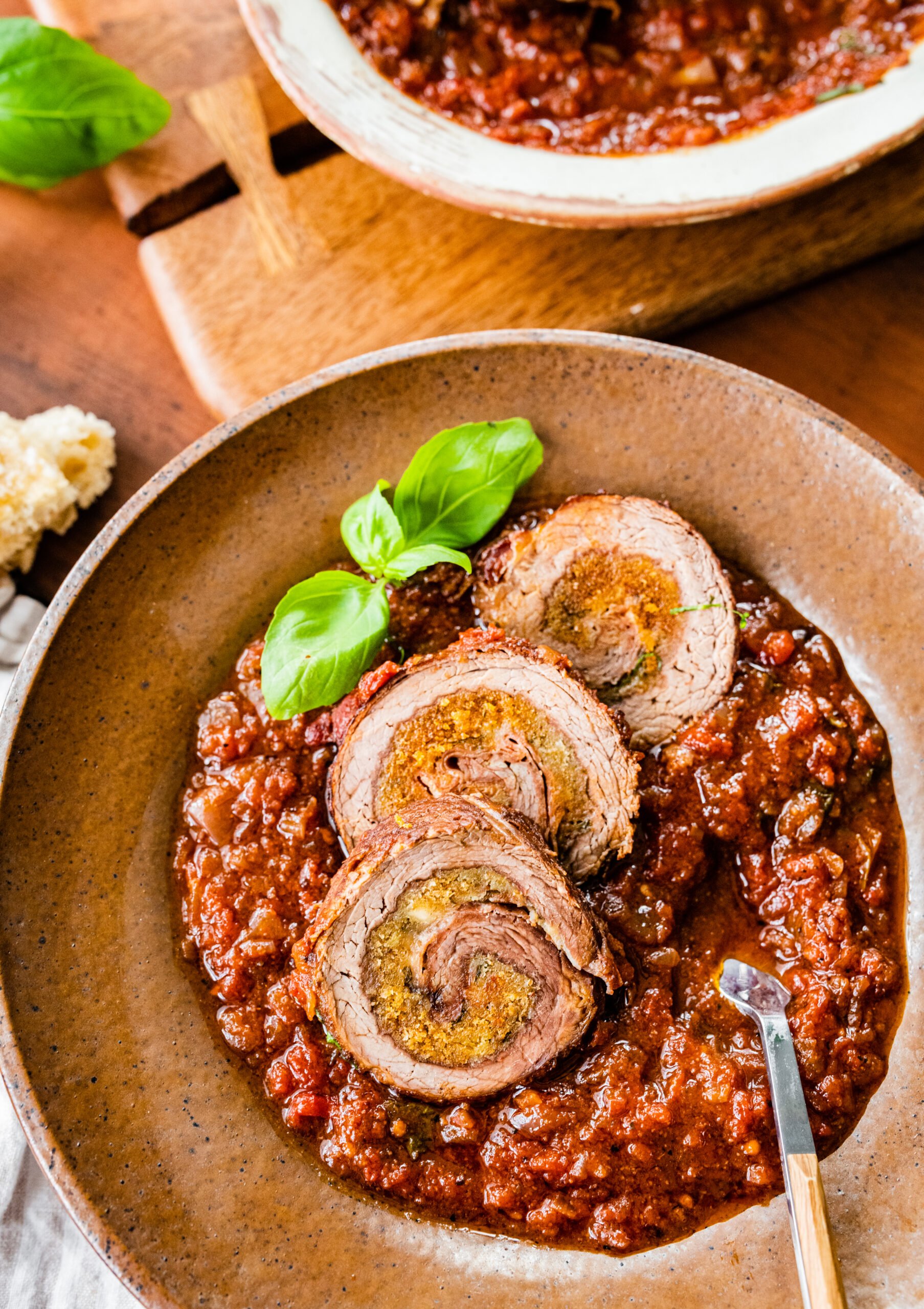 braciole slices on plate with sauce and bread for dipping.