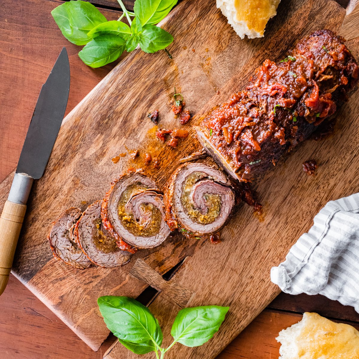 Sliced braciole with sauce on a cutting board