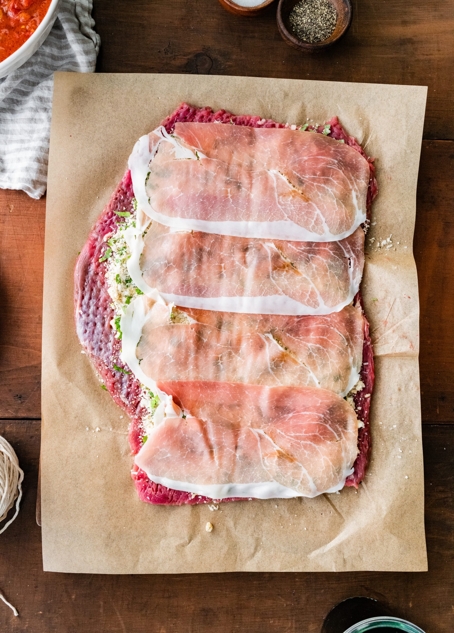 How to make Italian Braciole Process: layering the prosciutto on top of the breadcrumb mixture.