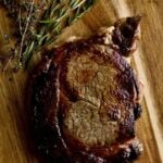 letting steak rest on a wood cutting board.