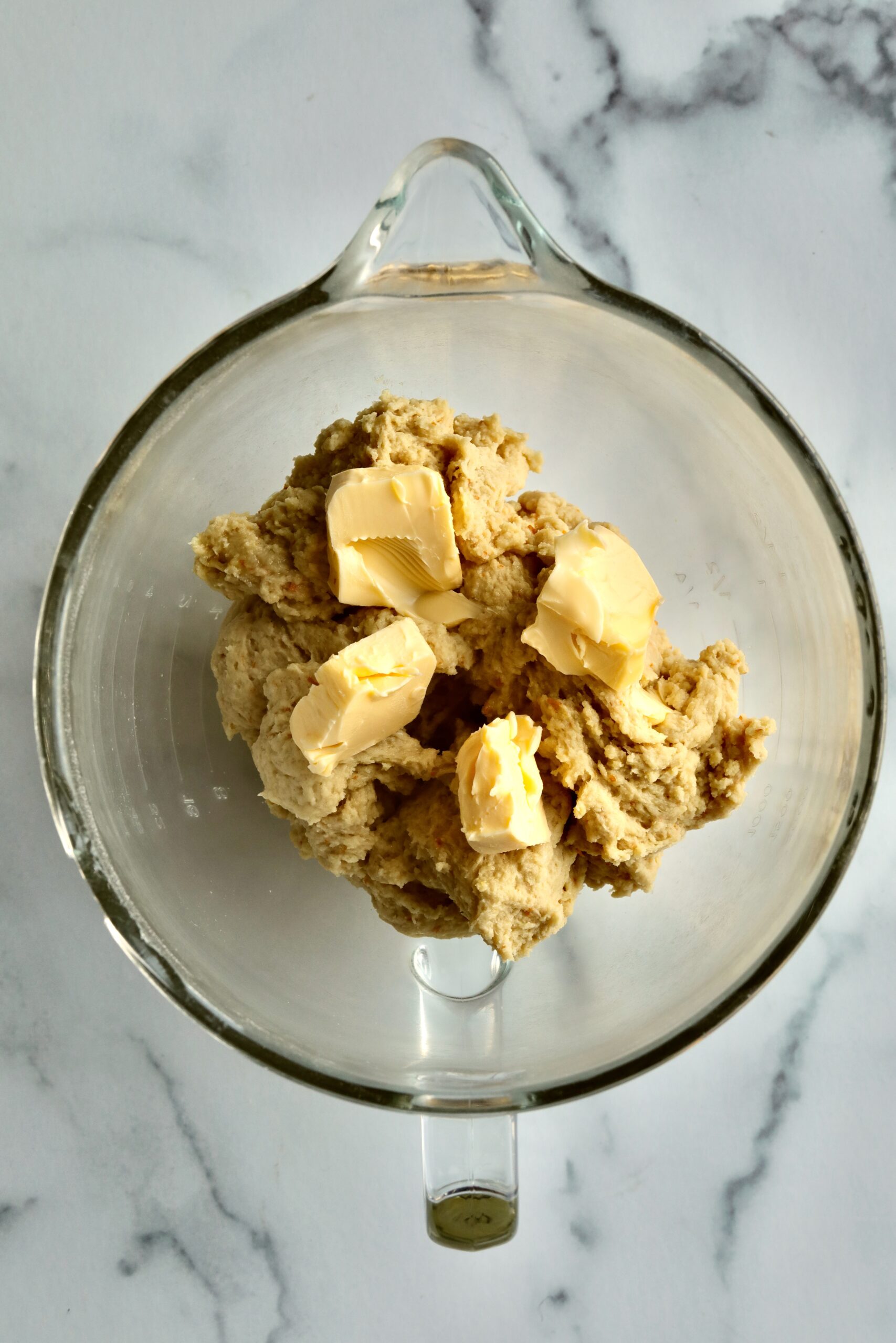 Process of making Bomboloni (how to make bomboloni recipe)- adding butter chunks to the dough.