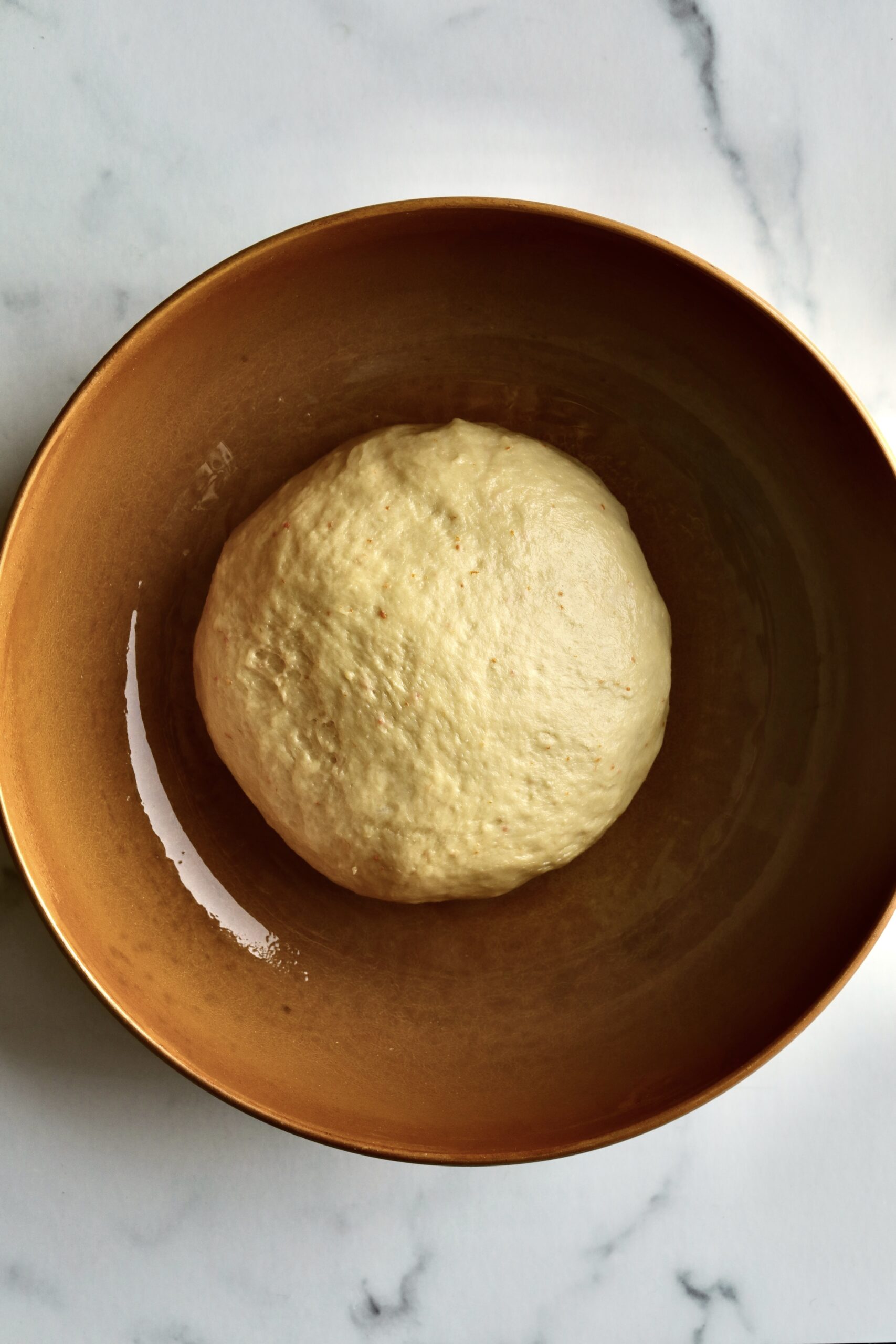 Process of making Bomboloni (how to make bomboloni recipe)- dough in greased bowl ready for first rise.