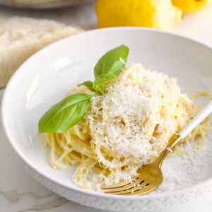 Fork on a plate of lemon pasta recipe topped with basil.