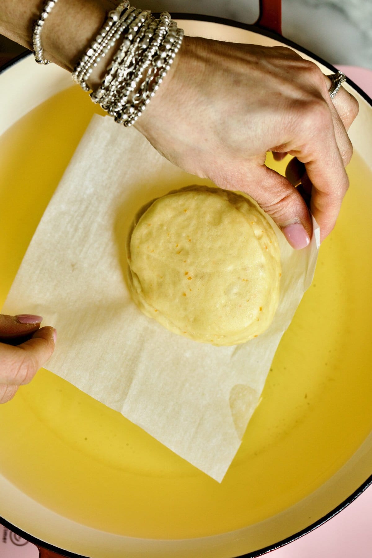 Process of making Bomboloni (how to make bomboloni recipe)- frying the donuts in oil- carefully placing parchment paper in hot oil to fry.