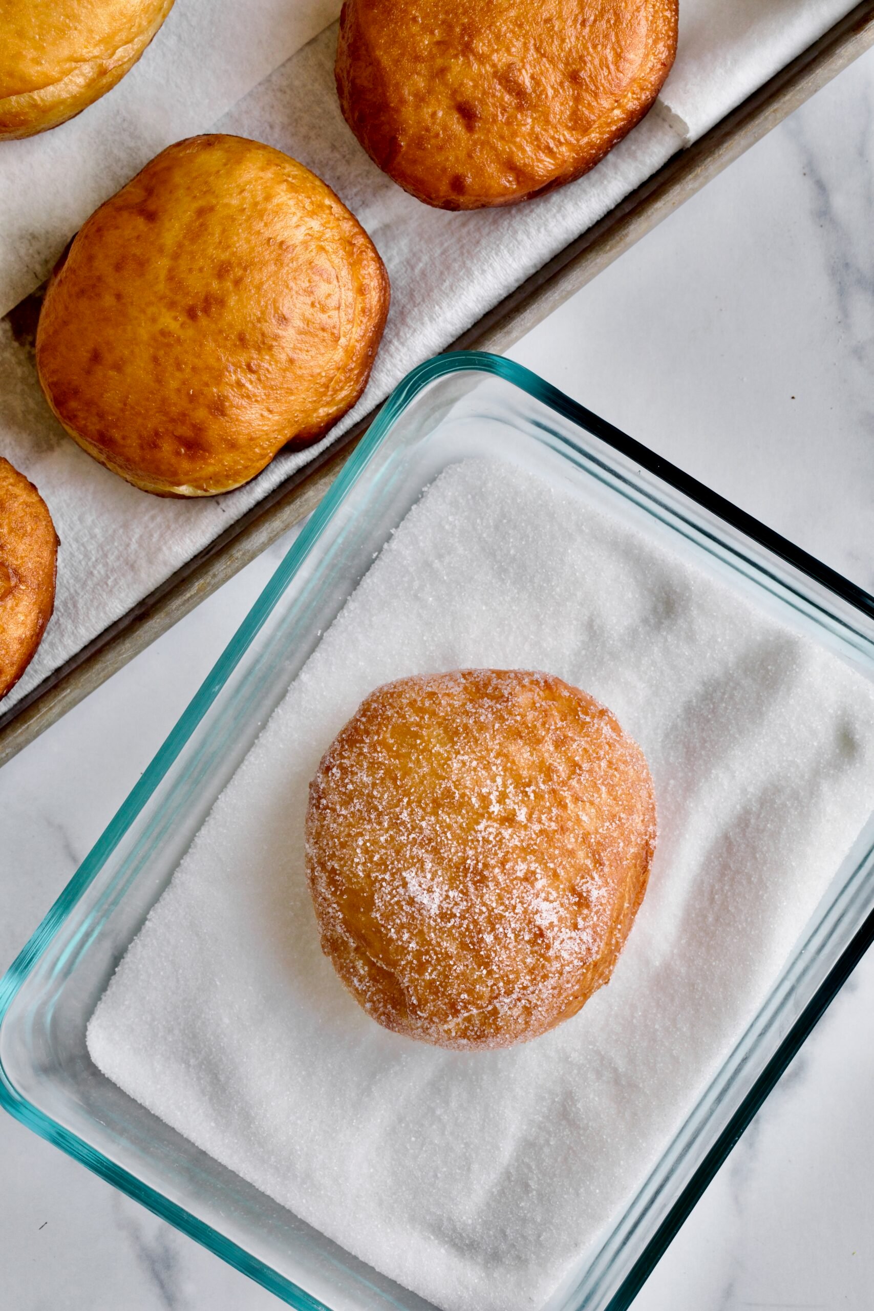 Process of making Bomboloni (how to make bomboloni recipe)- rolling the warm donut in sugar.