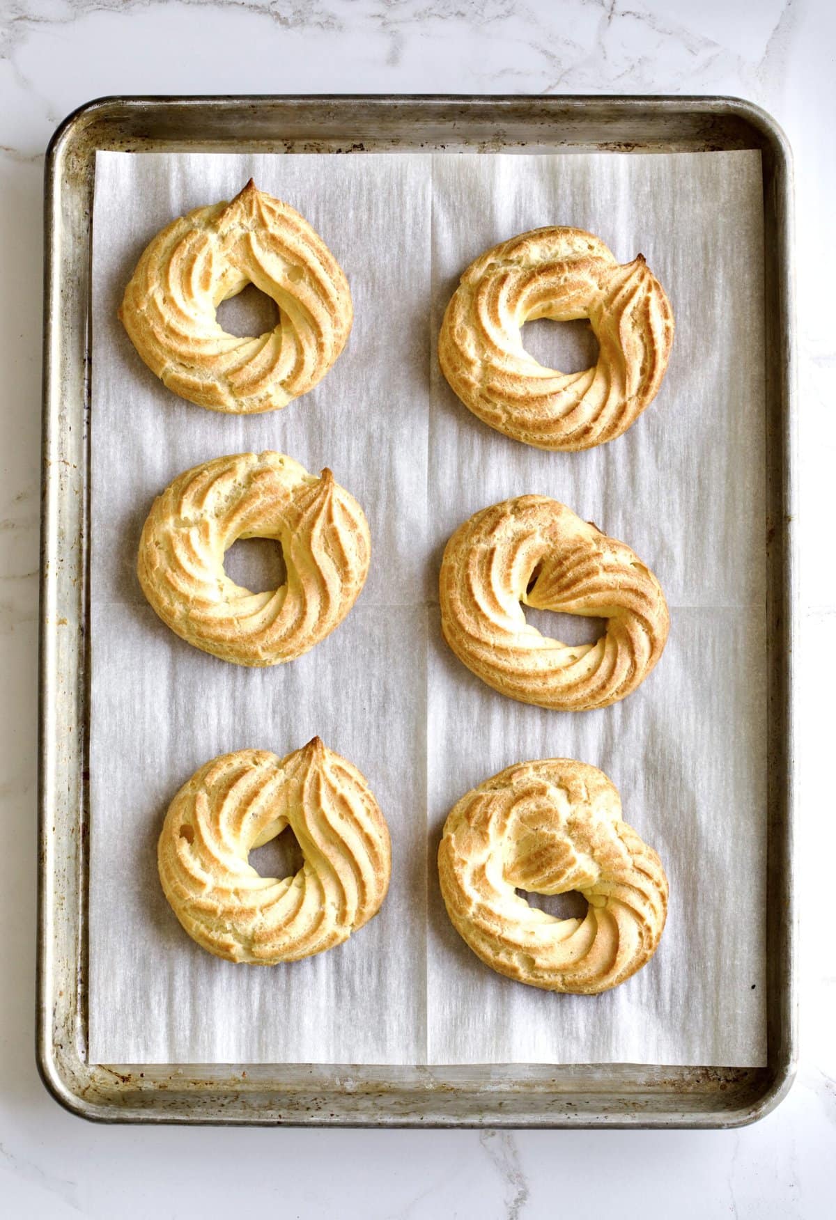 Process of making Baked Zeppole Di San Giuseppe Recipe (Italian)- baked choux pastry cooling on baking sheet.