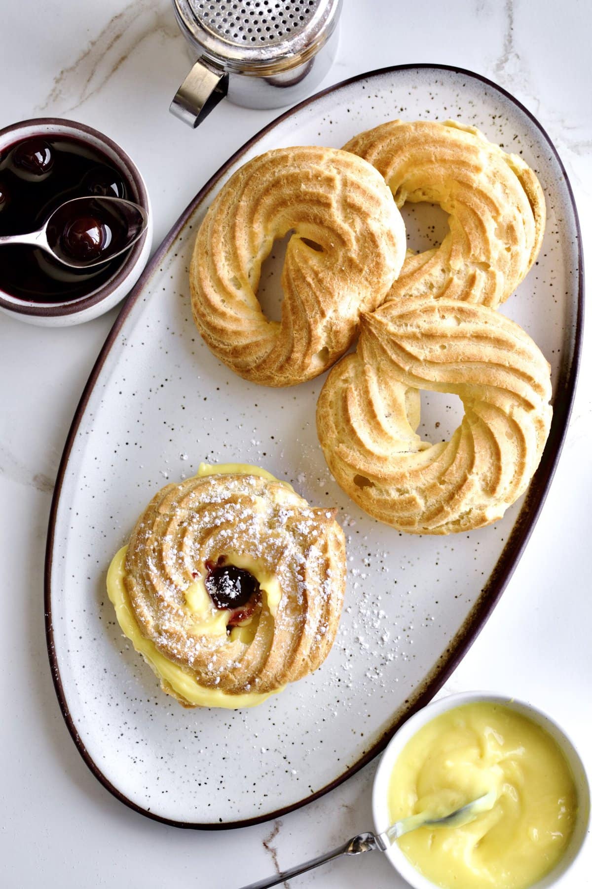 Process of making Baked Zeppole Di San Giuseppe Recipe (Italian)- baked zeppole filled with pastry cream add other half of pastry back to top and add amarena cherries on top.