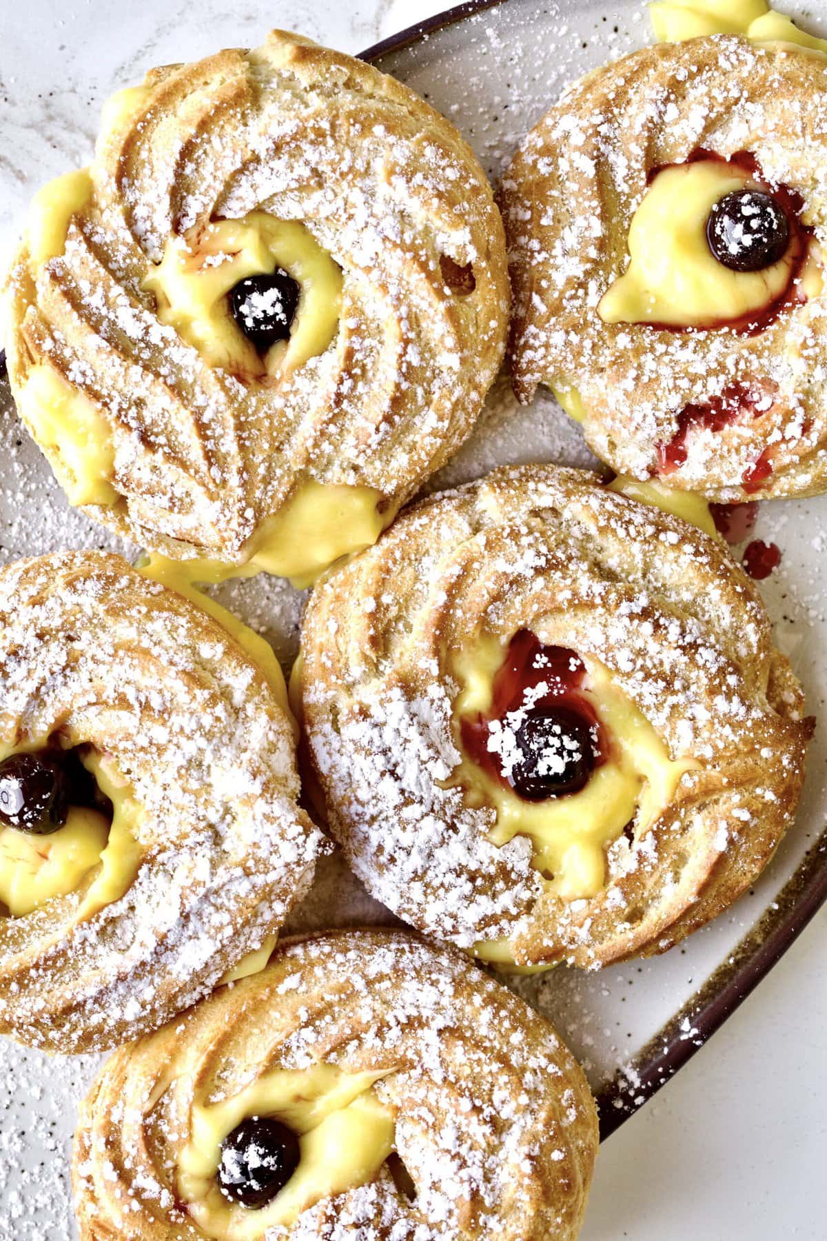 close up of finished baked zeppole  filled with Italian pastry cream and Italian Amarena cherries. 