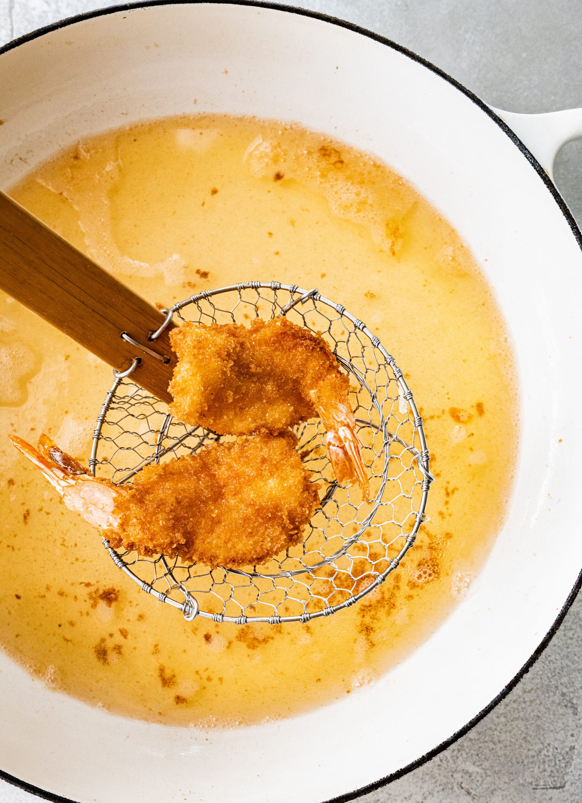 process for how to make Fried Butterfly Shrimp Recipe (Easy and Crunchy)- taking out the shrimp with a slotted spoon.