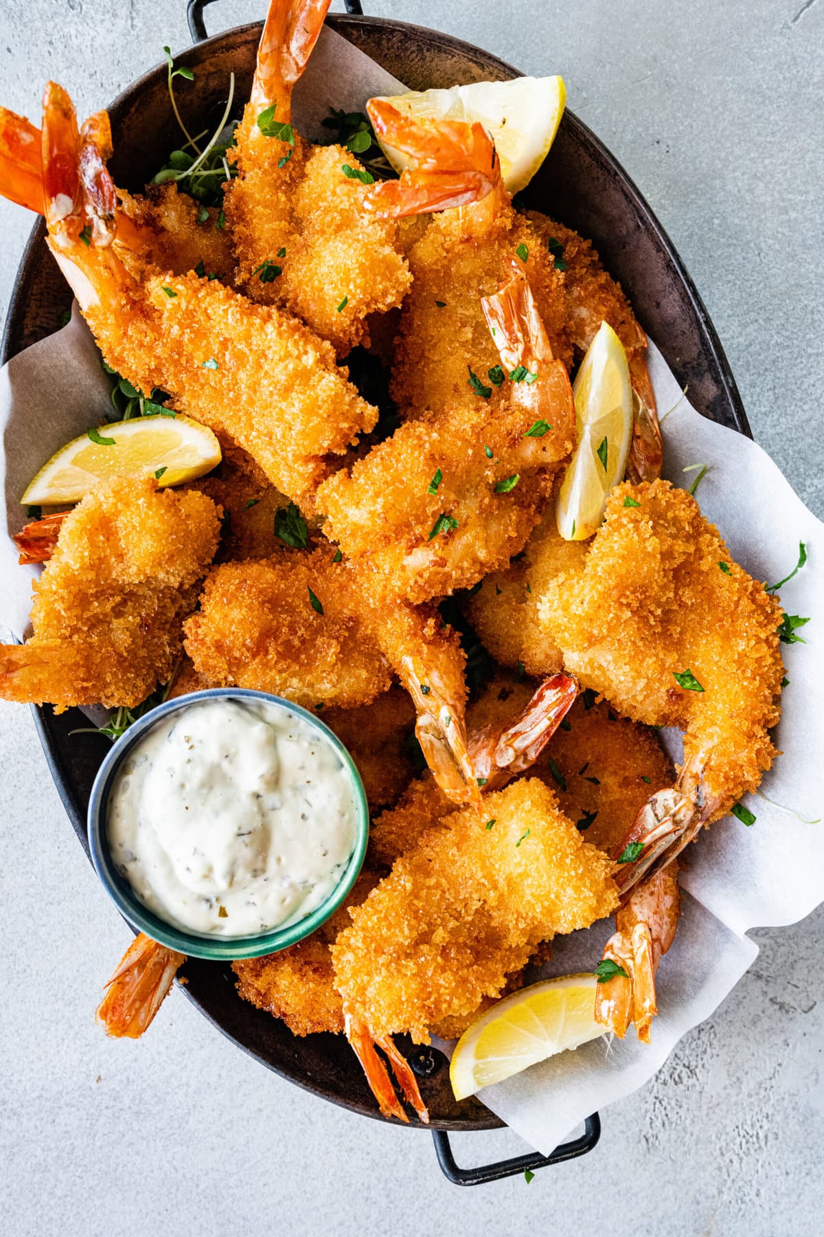 Fried shrimp on serving platter with lemon wedges, parsley, and tartar sauce.