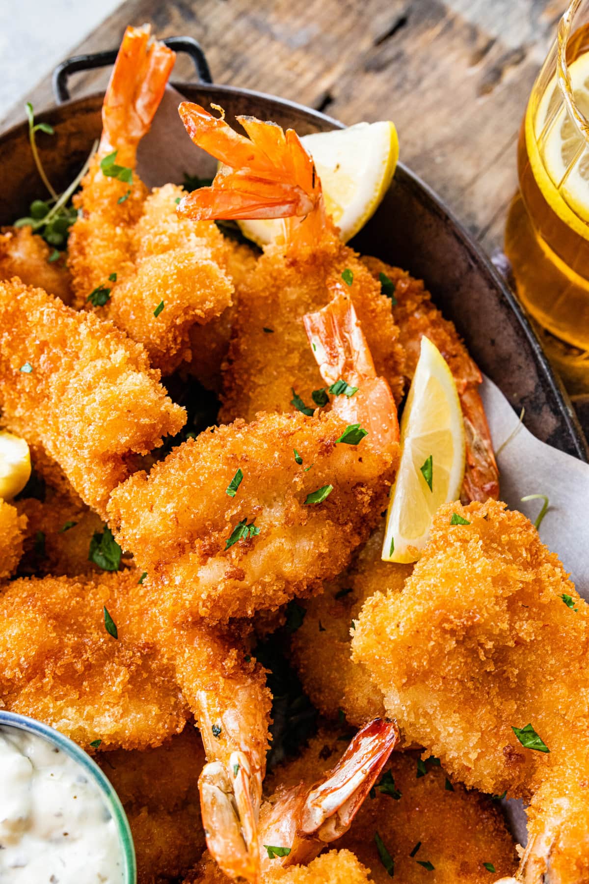 Fried shrimp on serving platter with lemon wedges, parsley, and tartar sauce.