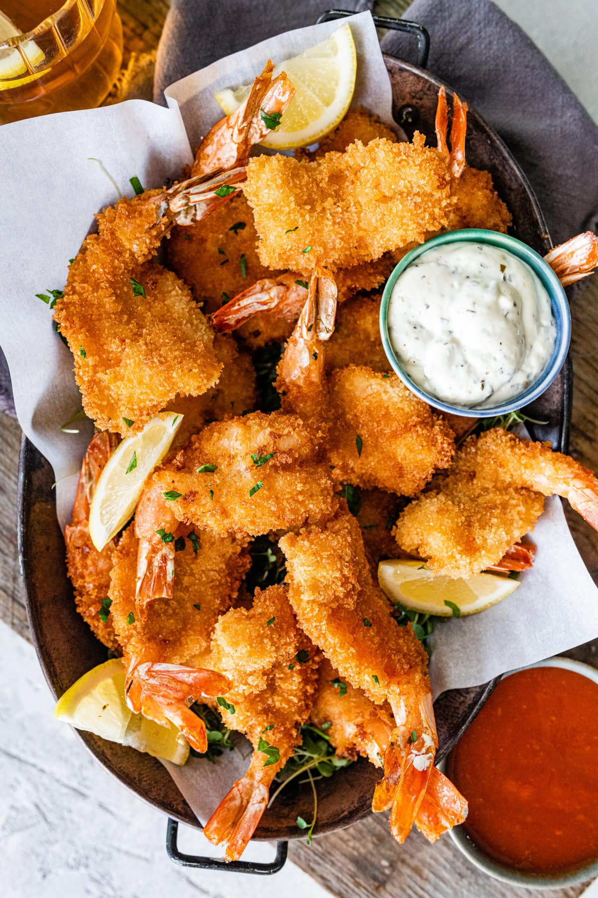 Fried shrimp on serving platter with lemon wedges, parsley, and tartar sauce. and cocktail sauce.