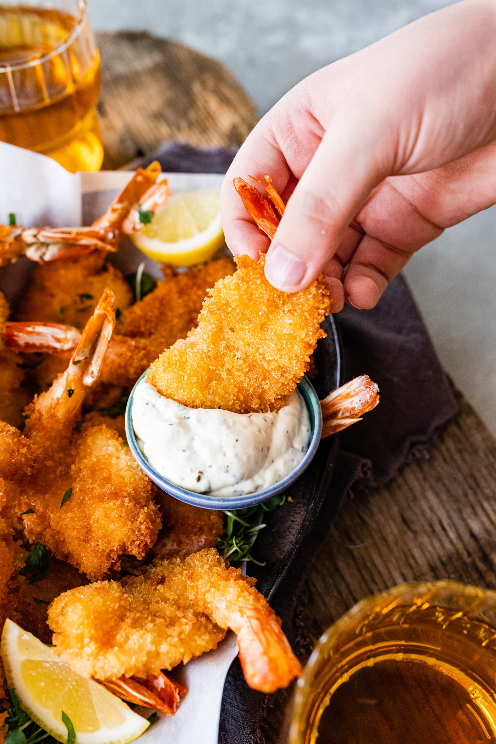 Hand dipping fried shrimp into tartar sauce.