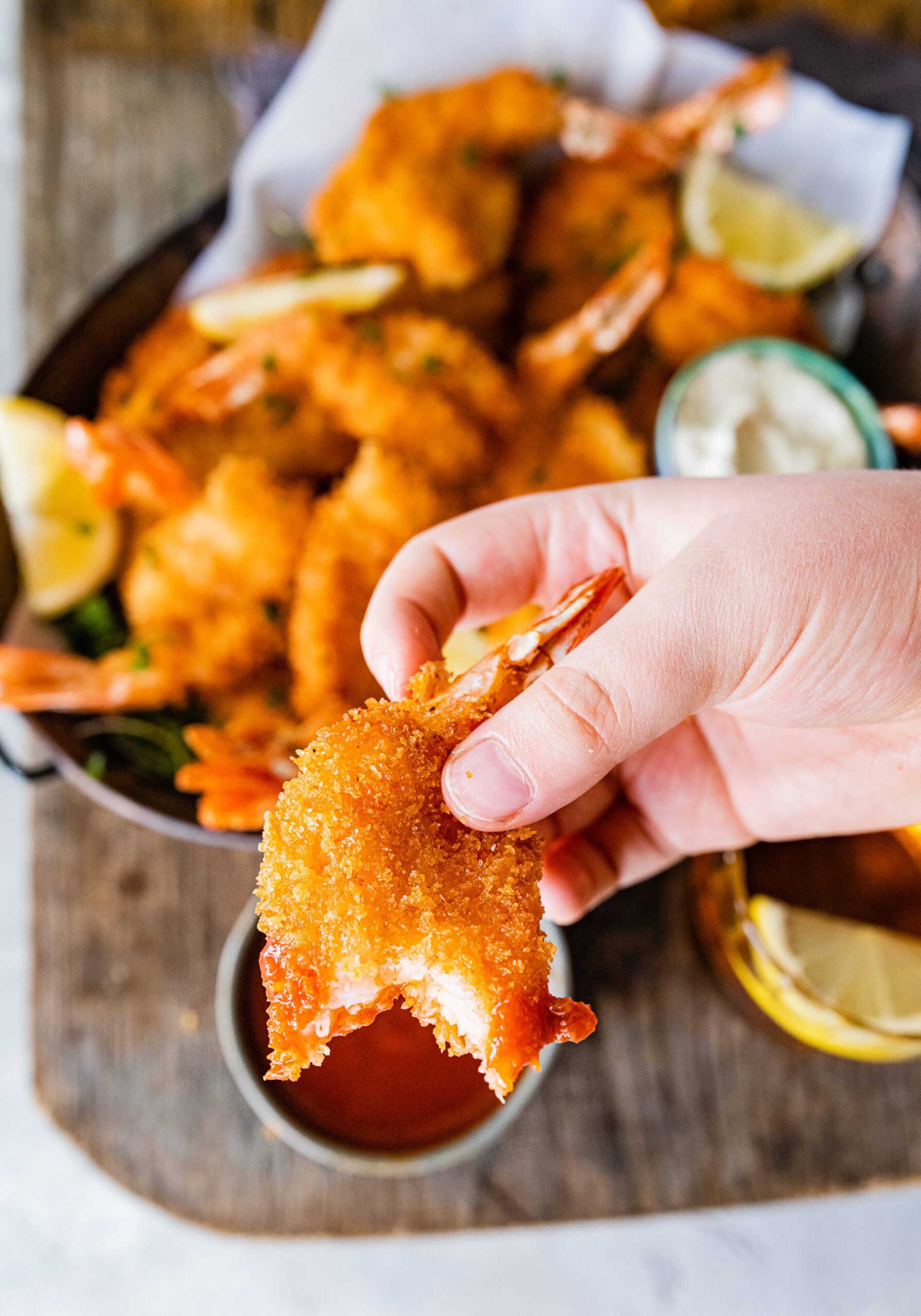 hand holding fried shrimp with a bite taken out of it.