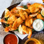 Fried shrimp on serving platter with lemon wedges, parsley, and tartar sauce. and cocktail sauce.