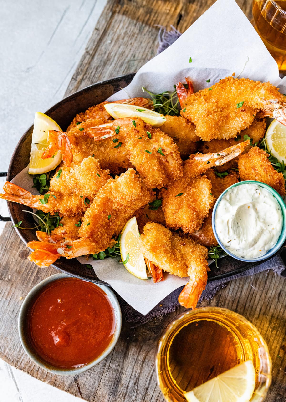 Fried shrimp on serving platter with lemon wedges, parsley, and tartar sauce. and cocktail sauce.