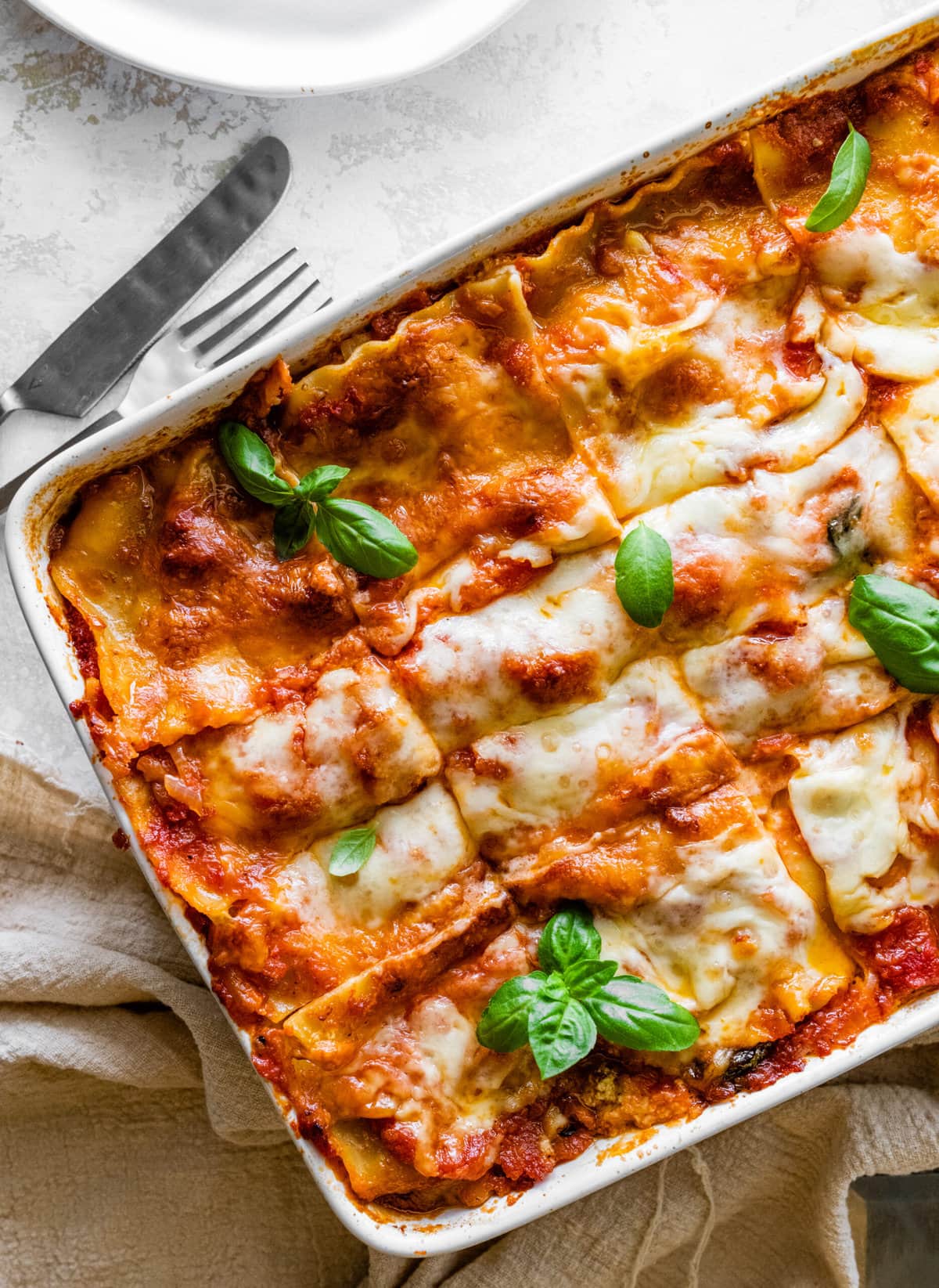 cut in slices of the mediterranean lasagna after it is baked in the oven with a cheesy top. Basil leaves as garnish.